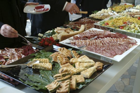 Eine Auswahl an Vorspeisen, Käse, Wurst und frischem Obst auf einem Buffet.