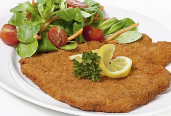 Panierte Schnitzel mit Zitronenscheiben und frischem gemischtem Salat.