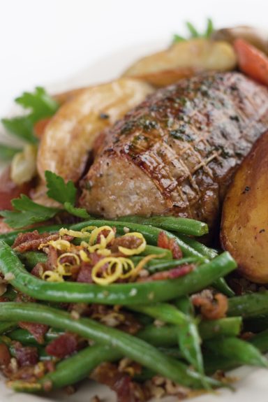 Geröstetes Fleisch mit grünem Gemüse, Kartoffeln und frischen Kräutern.