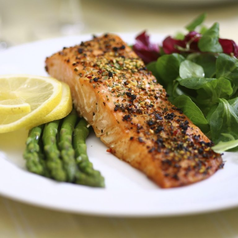 Gegrillter Lachs mit Zitronenscheiben, Spargel und gemischtem Salat.