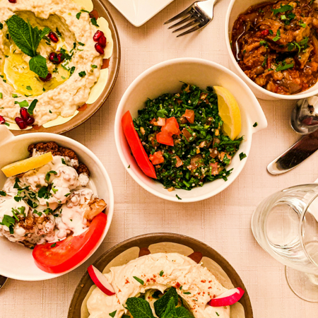 Verschiedene Schalen mit Salat, Hummus, gefüllten Gemüse und einem herzhaften Gericht.