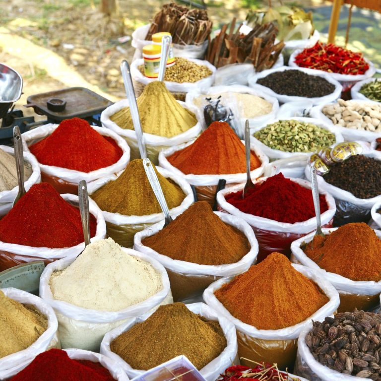 Bunte Gewürze in Säcken auf einem Markt, in verschiedenen Farben und Texturen.