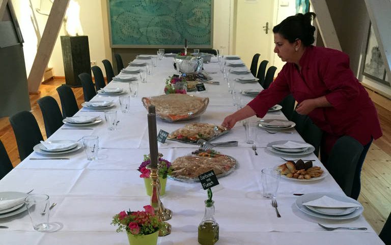 Al-Layal-Service: perfekt gedeckte Tafel. Chefin Yamama Schnelle von Al-Layal beim Eindecken einer festlichen Tafel mit Geschirr und Speisen.