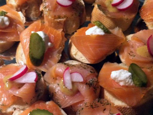 Bunt belegte Häppchen mit Lachs, Gurken, Radieschen und Paprika auf einem Tablett.