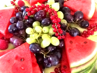 Bunte Obstplatte mit Wassermelone, Trauben, Johannisbeeren und Himbeeren.